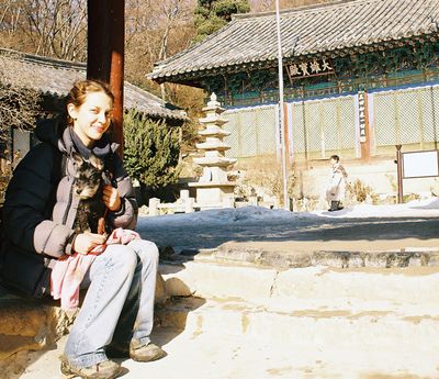 Woman and dog sitting on the steps a Korean temple gate
